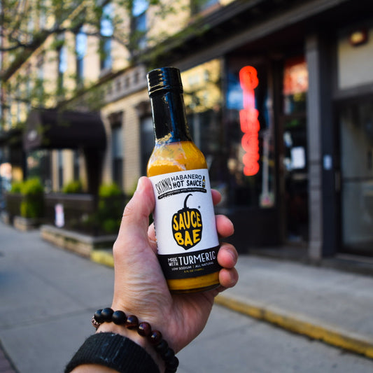 Picture of hand holding bottle of Sauce Bae