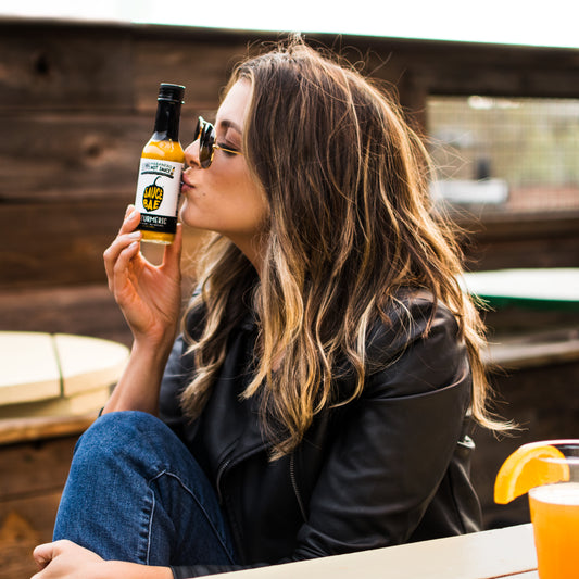 Picture of cute girl kissing a bottle of Sauce Bae Skinny Habanero Hot Sauce